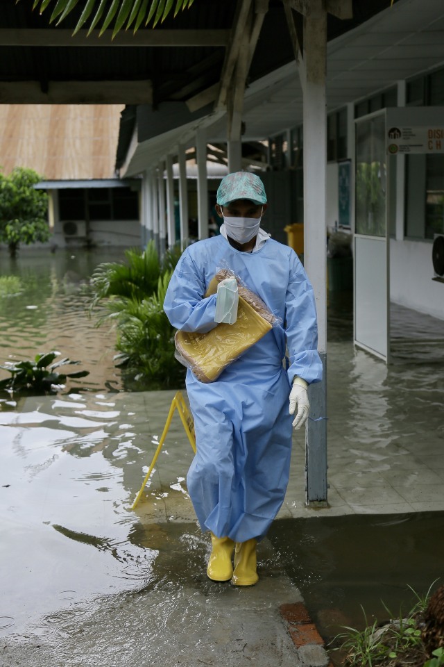 Petugas medis di ruang isolasi pinere RSUDZA Banda Aceh berjalan di genangan banjir akibat hujan yang terus mengguyur. Foto: Abdul Hadi/acehkini