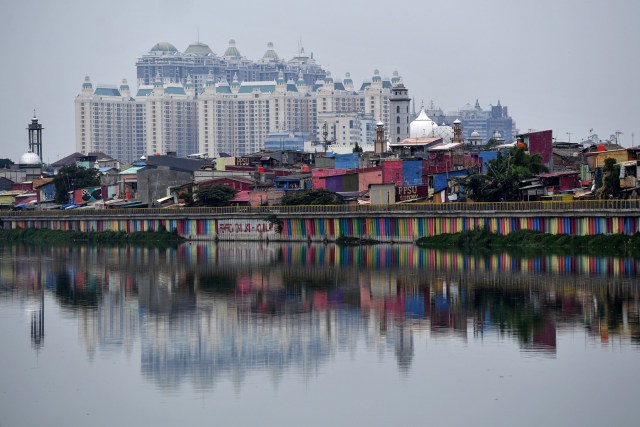 Warga beraktivitas di rumahnya berlatar belakang hunian bertingkat di kawasan Sunter, Jakarta Utara, Sabtu (9/5/2020). Foto: ANTARA FOTO/Sigid Kurniawan