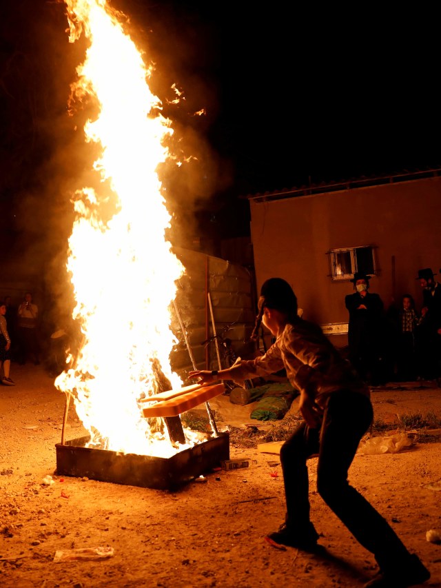 Salah satu anak merayakan Festival Api Unggun saat liburan Yahudi Lag Ba-Omer di lingkungan Mea Shearim di Yerusalem. Foto: REUTERS / Ronen Zvulun