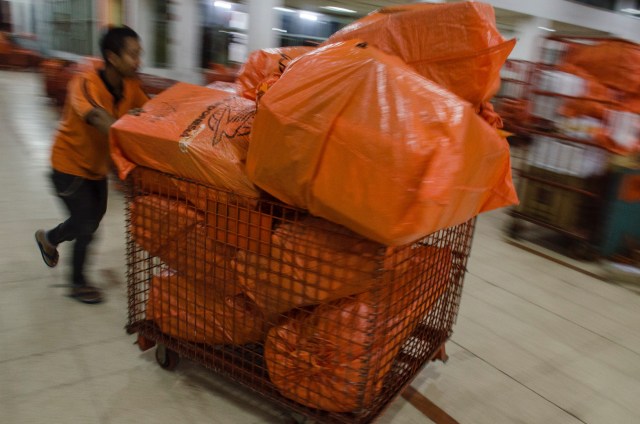 Seorang pekerja menyortir paket dan logistik yang akan didistribusikan di PT Pos Indonesia (Persero), Bandung, Jawa Barat, Kamis (14/5). Foto: Antara/Novrian Arbi