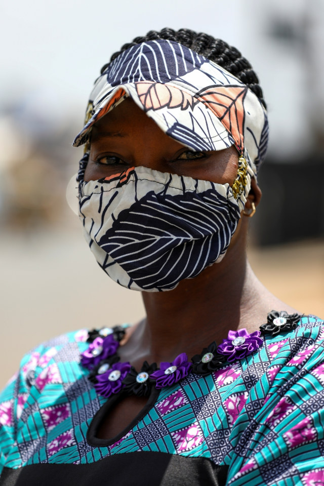 Model berpose dengan busana dan masker kain bermotif saat peragaan busana, di Lagos, Nigeria. Foto: REUTERS/Temilade Adelaja
