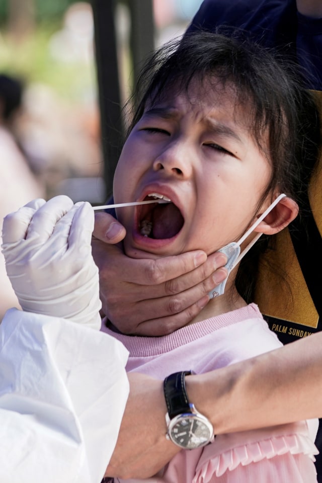 Seorang anak melakukan tes asam nukleat di Wuhan, Hubei, China, Sabtu (16/5).