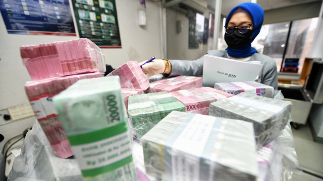 Seorang petugas bank mengecek uang kertas. PT Pura Group termasuk pemasok bahan baku kertas untuk uang tersebut. Foto: Dok. BTN