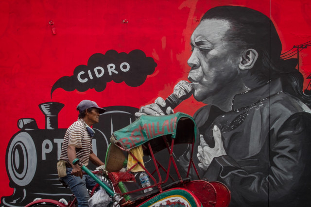 Warga melintas di depan mural bergambar penyanyi campursari almarhum Didi Kempot di jalan Arifin, Kampung Baru, Solo, Jawa Tengah, Selasa (19/5). Foto: ANTARA FOTO/Mohammad Ayudha