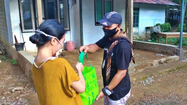 Jurnalis Banthayo.id, Burhan Undu, menyerahkan bantuan pangan kepada warga. Jumat, (22/5). Foto: Dok banthayo.id
