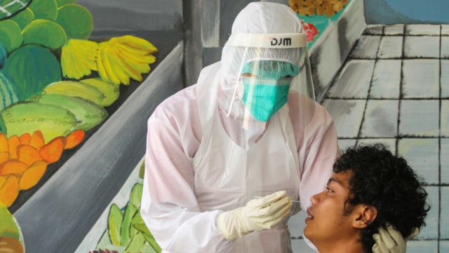 Petugas medis mengambil sampel lendir dari seorang pedagang saat tes swab di Pasar Cisalak, Depok, Jawa Barat. Foto: ANTARA FOTO/Asprilla Dwi Adha