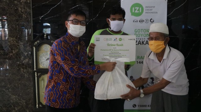 "Bazma Pertamina EP Apresiasi Aksi Bersama IZI di Kampung Nelayan Kalibaru" - Perwakilan Bazma Pertamina EP, Irfan (paling kiri), memberikan paket sembako kepada salah satu mustahik kampung nelayan Kalibaru, Cilincing. Dok. IZI