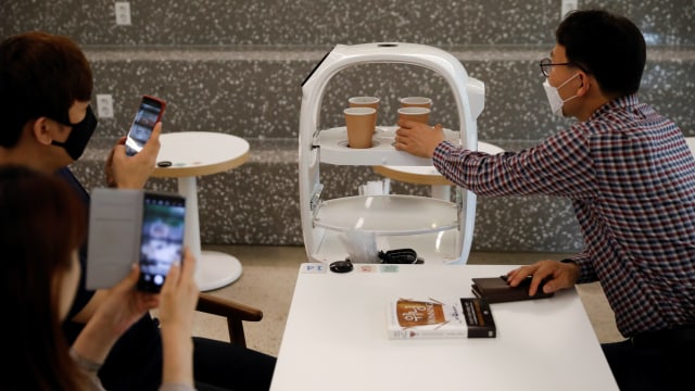 Sebuah robot yang menerima pesanan, membuat kopi dan membawa minuman langsung ke pelanggan di sebuah kafe di Daejeon, Korea Selatan, (25/5). Foto: REUTERS/Kim Hong-Ji