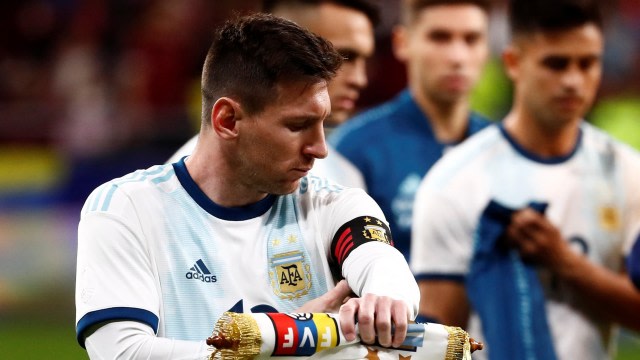 Lionel Messi memperbaiki ban kaptennya sebelum melawan Venezuela. Foto: REUTERS/Juan Medina