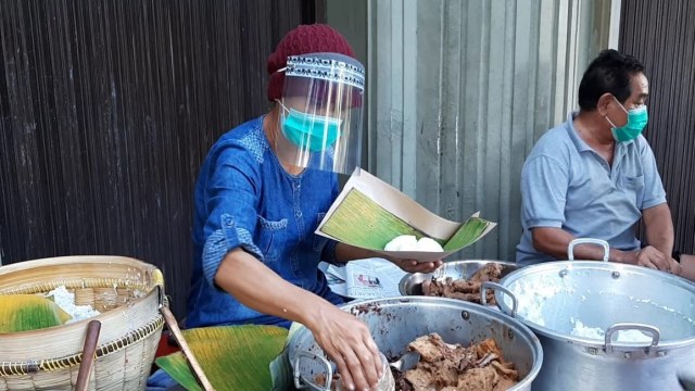 Sudarmi, pedagang gudeg di Jalan Urip Sumoharjo, Kota Yogyakarta, mengenakan face shield serta masker ketika melayani pembeli. Foto: Arfiansyah Panji/kumparan
