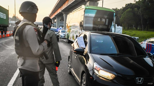 Petugas gabungan melakukan pemeriksaan terhadap pengguna kendaraan yang akan masuk ke wilayah DKI Jakarta di di KM 47 Tol Cikampek-Jakarta, Jawa Barat. Foto: ANTARA FOTO/Muhammad Adimaja