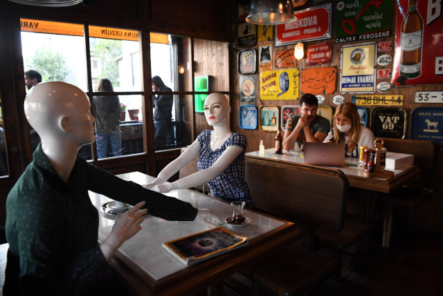Ilustrasi manekin ditempatkan di meja untuk mejaga jarak sosial (social distancing) di sebuah kafe. Foto: AFP/OZAN KOSE