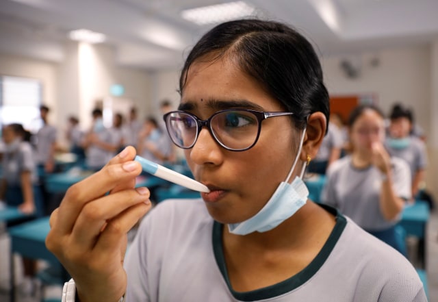 Siswa diperiksa suhu tubuh di Sekolah Menengah Yio Chu Kang di Singapura (2/6). Foto: REUTERS/Edgar Su