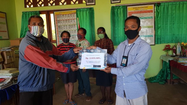 Penanggungjawab florespedia.com, Mario WP Sina menyerahkan secara simbolis donasi program kumparanDerma yang diterima oleh Kepala SDN Hepang, Paulus Ara Baha. Foto: istimewa. 