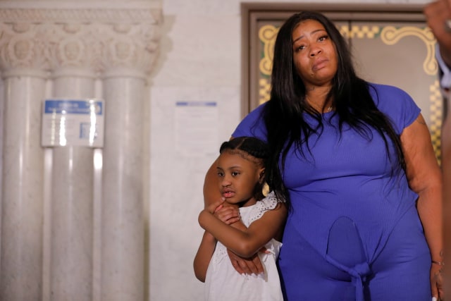 Anak perempuan George Floyd yang berusia 6 tahun, Gianna, dipeluk oleh ibunya, Roxie Washington sebelum berbicara tentang ayahnya di Balai Kota Minneapolis. Foto: REUTERS/Lucas Jackson