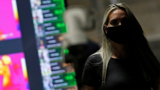 Seorang wanita yang mengenakan masker terlihat di depan kamera termal di stasiun bus pusat dan stasiun pusat Metro, Brasil. Foto: REUTERS/Adriano Machado