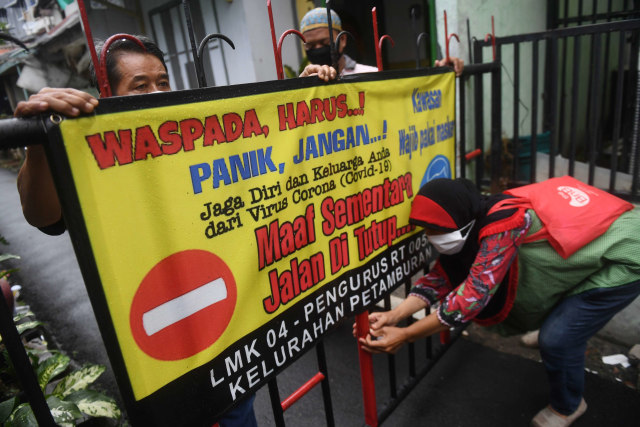 Warga memasang spanduk himbauan saat menutup jalan pada simulasi pelaksanaan Pembatasan Sosial Berskala Lokal (PSBL) di RT 05 RW 04, Petamburan. Foto: ANTARA FOTO/Akbar Nugroho Gumay