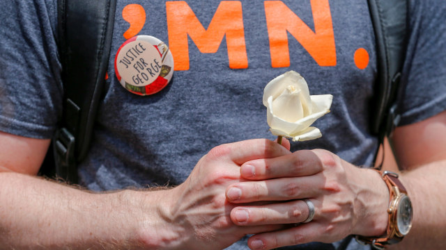 Seorang pria memegang mawar putih untuk mengenang memorial George Floyd di Minneapolis, Minnesota, AMerika Serikat. Foto: REUTERS / Eric Miller