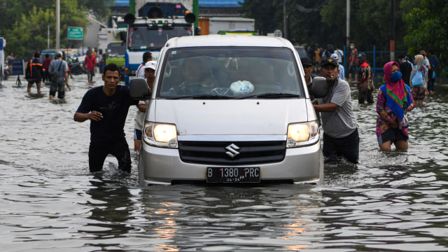 Warga mendorong mobil yang mogok saat melintasi banjir di kawasan Muara Baru, Penjaringan, Jakarta Utara, Jumat (5/6). Foto: ANTARA FOTO/M Risyal Hidayat