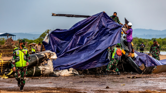 Petugas gabungan menutup bangkai helikopter yang jatuh menggunakan terpal di Kawasan Industri Kendal (KIK), Kabupaten Kendal, Jawa Tengah, Sabtu (6/6/2020). Foto: Aji Styawan/ANTARA FOTO
