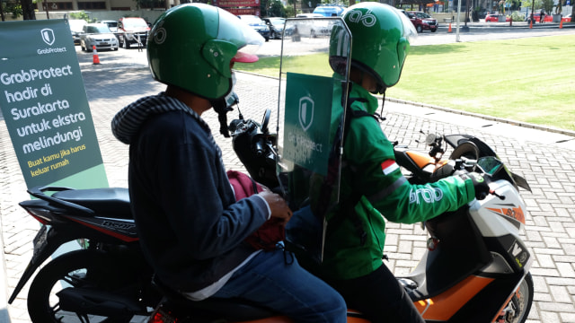 Penumpang menggunakan layanan ojek daring (ojol) yang dilengkapi fasilitas separator khusus di Balai Kota Solo, Jawa Tengah, Senin (8/6). Foto: Antara/Maulana Surya