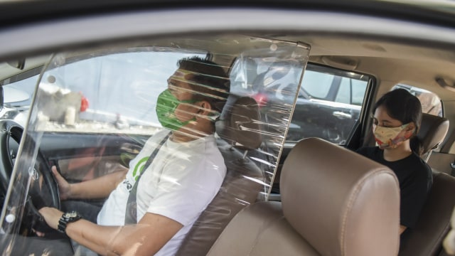 Penumpang turun dari taksi daring yang dipasangi sekat pelindung di kawasan jalan Kendal, Jakarta, Rabu (10/6). Foto: ANTARA FOTO/Galih Pradipta