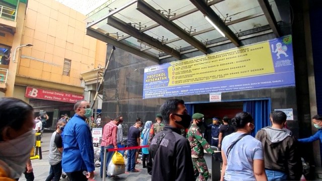 Pengunjung mengantre untuk mencuci tangan dan melakukan pemeriksaan suhu tubuh di pintu masuk Pasar Tanah Abang Blok A Pintu Timur, Senin (15/6). Foto: Livia Kristianti/ANTARA