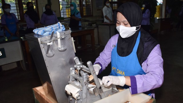 Pekerja mengenakan sarung tangan dan masker saat melinting rokok sigaret kretek tangan di pabrik rokok PT Digjaya Mulia Abadi (DMA) di Jawa Timur. Foto: SISWOWIDODO/ANTARA FOTO