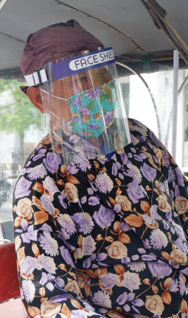 Sadiyo (63), kusir andong mengenakan face shield ketika bekerja. Foto: Arfiansyah Panji Purnandaru/kumparan