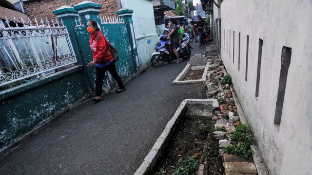 Warga melintas di samping kuburan yang berada di akses jalan lingkungan warga daerah Pisangan, Jakarta Timur.  Foto: Fakhri Hermansyah/ANTARA FOTO