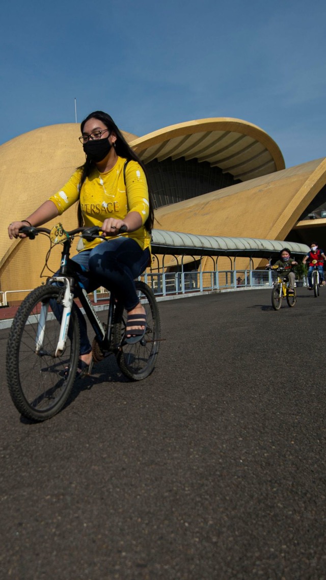 Pengunjung bersepeda melintas di depan Teater I-Max Keong Mas di Taman Mini Indonesia Indah (TMII), Jakarta. Foto: ANTARA FOTO/Aditya Pradana Putra