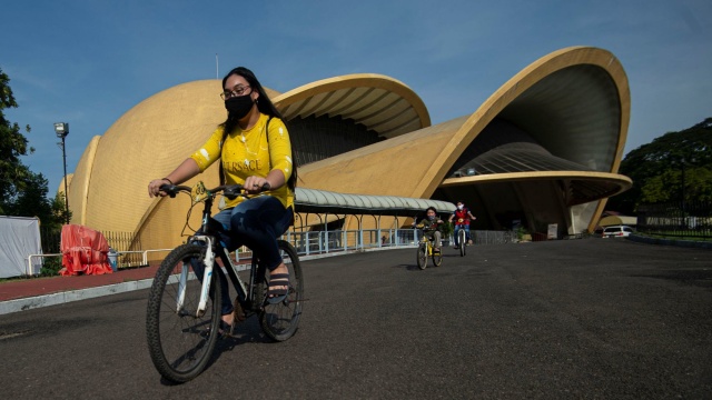 Pengunjung bersepeda melintas di depan Teater I-Max Keong Mas di Taman Mini Indonesia Indah (TMII), Jakarta. Foto: ANTARA FOTO/Aditya Pradana Putra