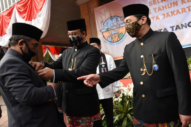 Gubernur DKI Jakarta Anies Baswedan (tengah) didampingi Wakil Gubernur Ahmad Riza Patria (kanan) merapikan pakaian anggota Bamus Betawi saat menghadiri upacara. Foto: Indrianto Eko Suwarso/ANTARA FOTO