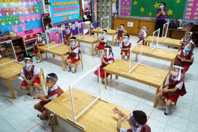 Siswa taman kanak-kanak sekolah Wichuthit memakai masker dan pelindung wajah menghadiri kelas saat kembali sekolah di Bangkok, Thailand. Foto: Athit Perawongmetha / REUTERS