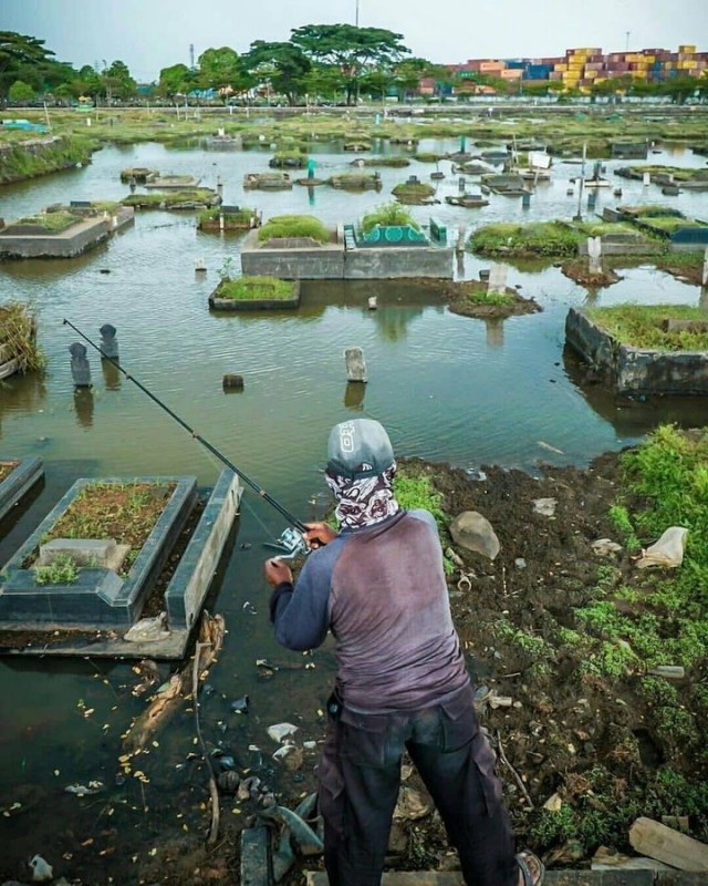 Viral warga memcing di kuburan yang tergenang air. (Foto: Tangkapan Layar Twitter @Kenyeaal)