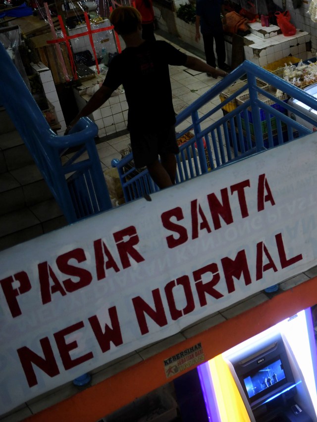 Warga melewati tangga di Pasar Santa yang bertuliskan new normal. Foto: Wahyu Putro A/ANTARA FOTO