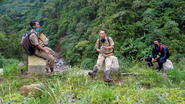 Kepala Sekolah SMP N 4 Bawang Mulud Sugito (tengah) dan guru Wiyata Bhakti beristirahat di sela-sela perjalananmengantar lembar tugas siswa secara langsung. Foto: Aditya Pradana Putra/Antara Foto