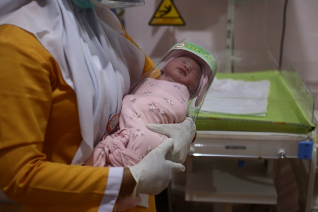 Ilustrasi perawat dan bayi baru lahir memakai face shield di RS Avicenna, Bireuen, Aceh. Foto: Amanda Jufrian untuk acehkini 