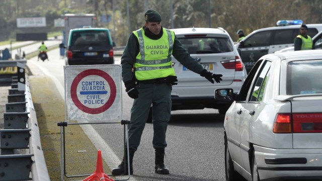 Seorang Penjaga Sipil Spanyol menghentikan mobil di perbatasan Spanyol-Portugal antara Tui dan Valenca. Foto: Miguel Riopa/AFP