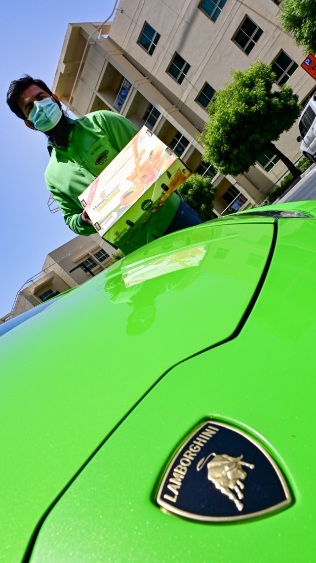 Muhammad Jehanzeb, direktur pelaksana Pakistan Super Market Dubai, berdiri di sebelah mobil sport Lamborghini Huracan sambil memegang pesananan mangga. Foto: GIUSEPPE CACACE / AFP