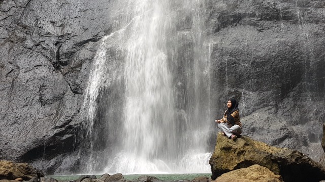 Salah seorang pengunjung berfoto dengan latar belakang air terjun. Foto: Adi Pallawalino/sulbarkini