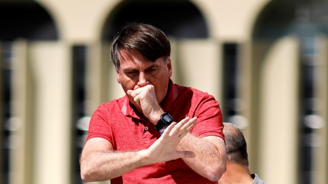 Presiden Brasil Jair Bolsonaro terlihat batuk-batuk saat menghadiri demonstrasi menentang lockdown di Brasilia, Brasil pada 19 April 2020. Foto: Sergio LIMA/AFP