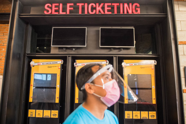 Pekerja menggunakan alat pelindung wajah di depan tempat tiket saat simulasi pembukaan dan peninjauan tempat hiburan bioskop CGV Cinemas di Bandung. Foto: M Agung Rajasa/ANTARA FOTO