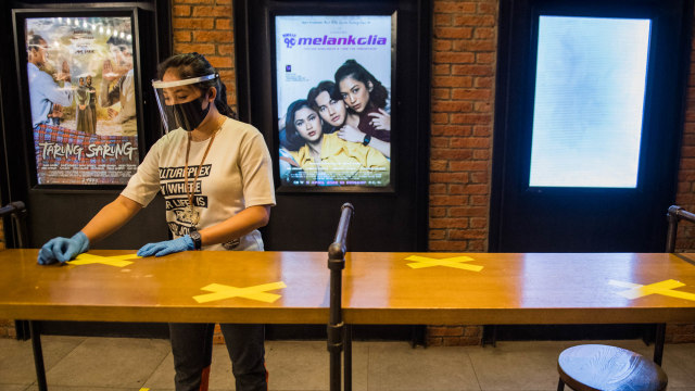 Pekerja membersihkan meja saat simulasi pembukaan dan peninjauan tempat hiburan bioskop CGV Cinemas di Bandung. Foto: M Agung Rajasa/ANTARA FOTO