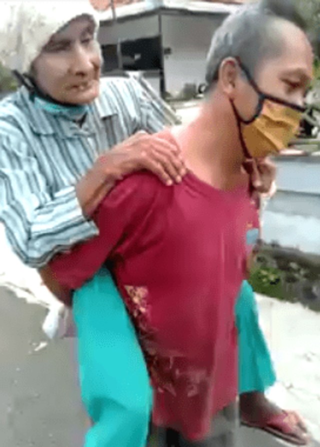 Ketua RT di Banyuwangi tergopoh-gopoh jalan kaki gendong lansia ke posko bantuan virus corona, Foto: Facebook Yuni Rusmini