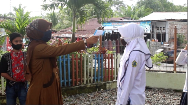 Siswa yang terlanjur ke sekolah dicek suhu tubuhnya. Foto: Siti Aisyah/acehkini