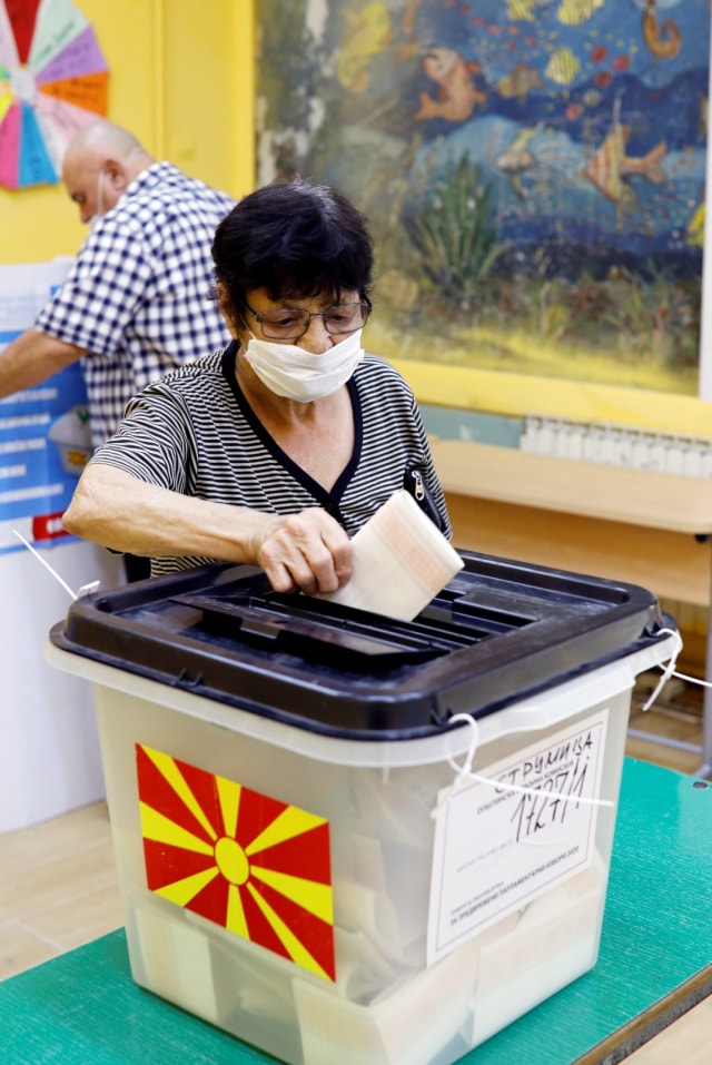 Seorang wanita mengenakan masker saat memasukan suarat suara di tempat pemungutan suara di Strumica, Makedonia Utara, Rabu (15/7). Foto: Ognen Teofilovski/Reuters