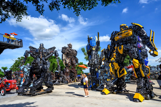 Sejumlah pengunjung befoto dengan latar robot Transformers yang terbuat dari potongan logam di Museum Ban Hun Lek, Ang Thong, Thailand. Foto: Mladen ANTONOV / AFP
