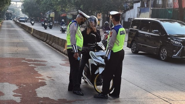 Polisi lalu lintas memberhentikan seorang pengendara sepeda motor melintas jalur Busway di Jalan Buncit Raya, Jakarta Selatan. Foto: Twitter/@TMCPoldaMetro
