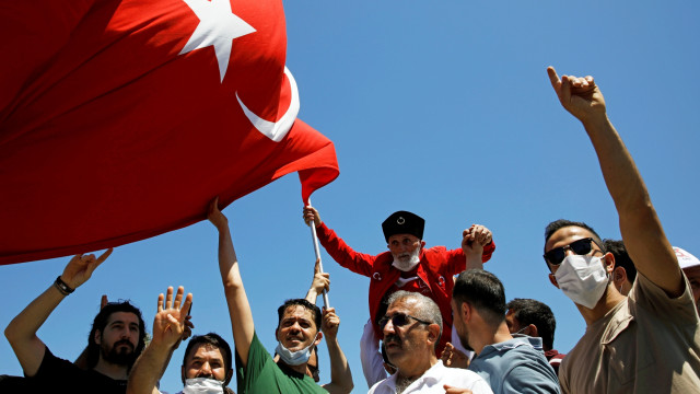 Sejumlah pria mengibarkan bendera menjelang salat Jumat perdana di luar Masjid Agung Hagia Sophia, di Istanbul, Turki, Jumat (24/7). Foto: REUTERS